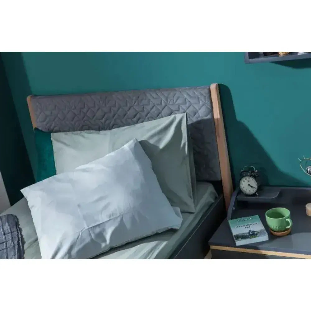 Loft Bed with light green sheets, pillows, quilted dark gray headboard, and light wood frame